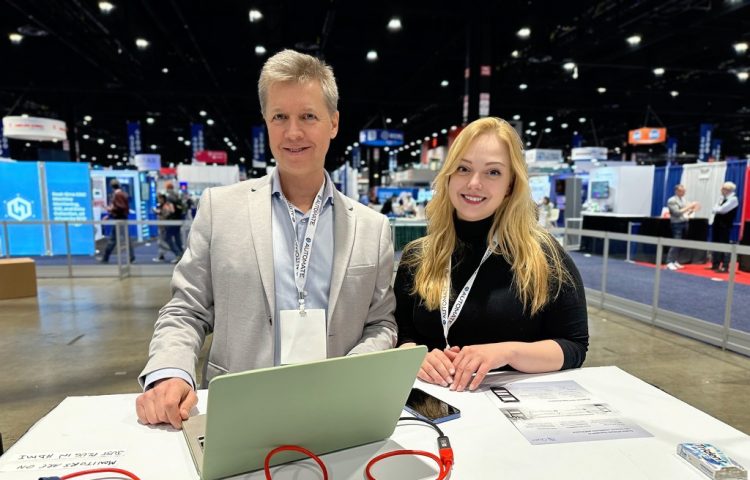 Vlad Lebedev and Alena Shumova present the Model C2 autonomous mobile robot at the Automate 2024 tradeshow, showcasing the robotic cart's self-navigation amd obstacle avoidance abilities.